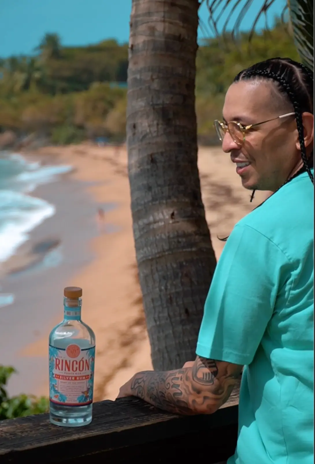 Beachside portrait beside a palm tree with Rincón rum