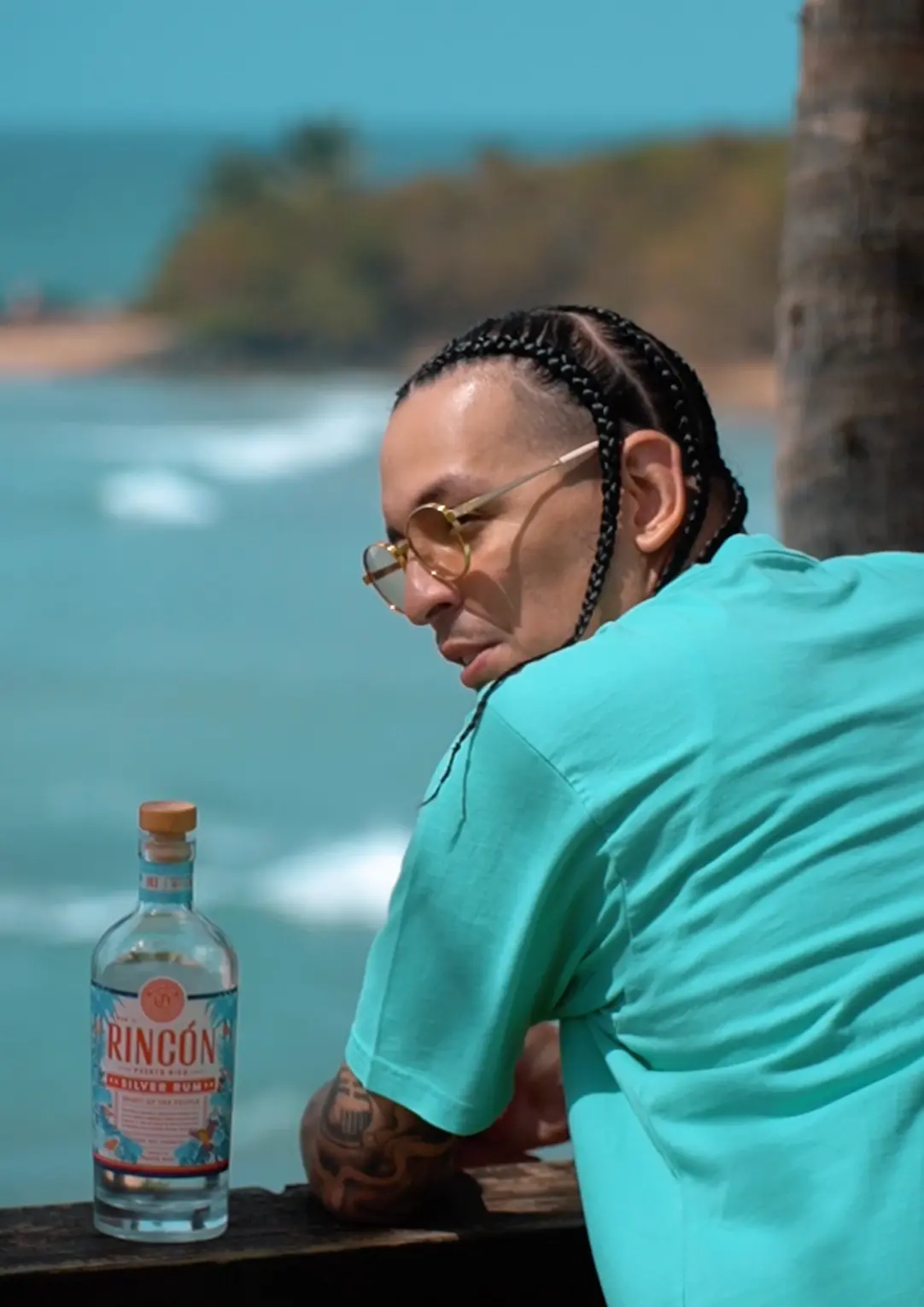 Artist seated by the beach with a bottle of Rincón Silver Rum