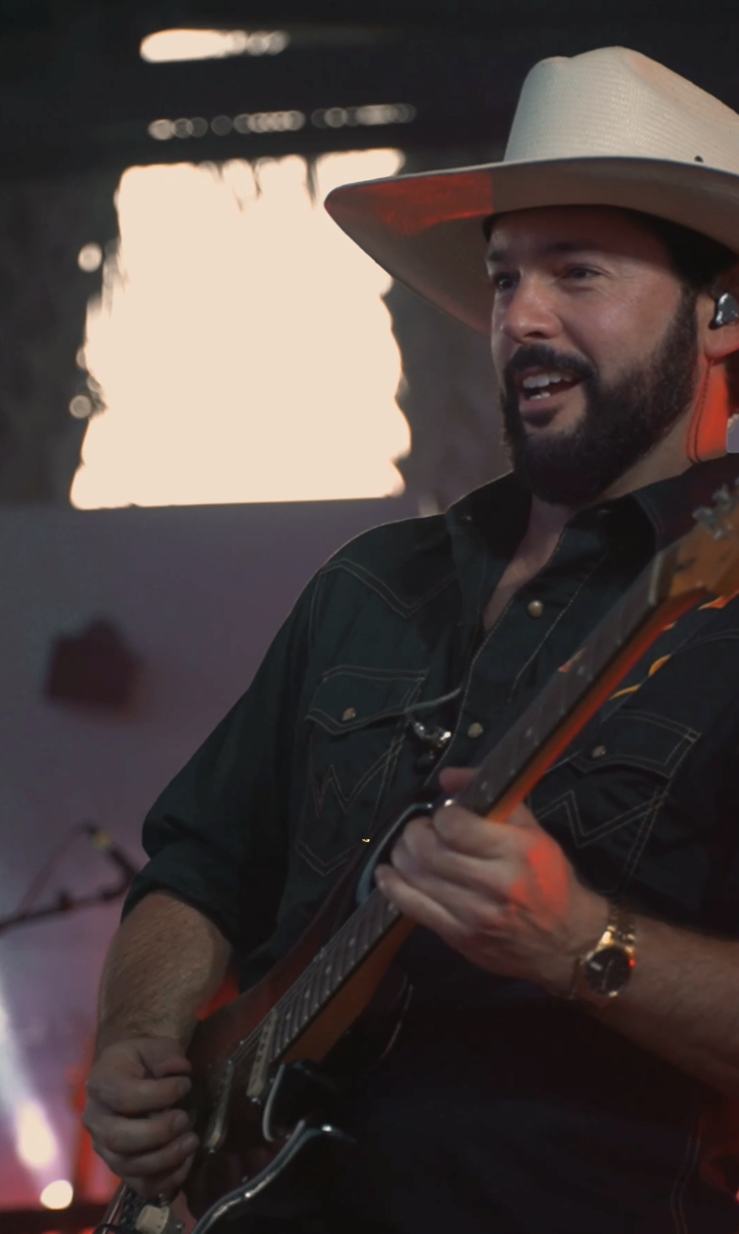 Guitarist performing live on stage in a cowboy hat