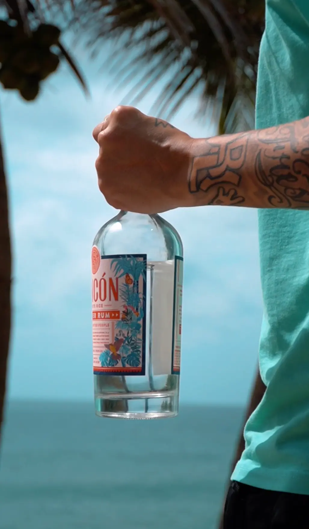 Rincón Silver Rum bottle held against a tropical seascape