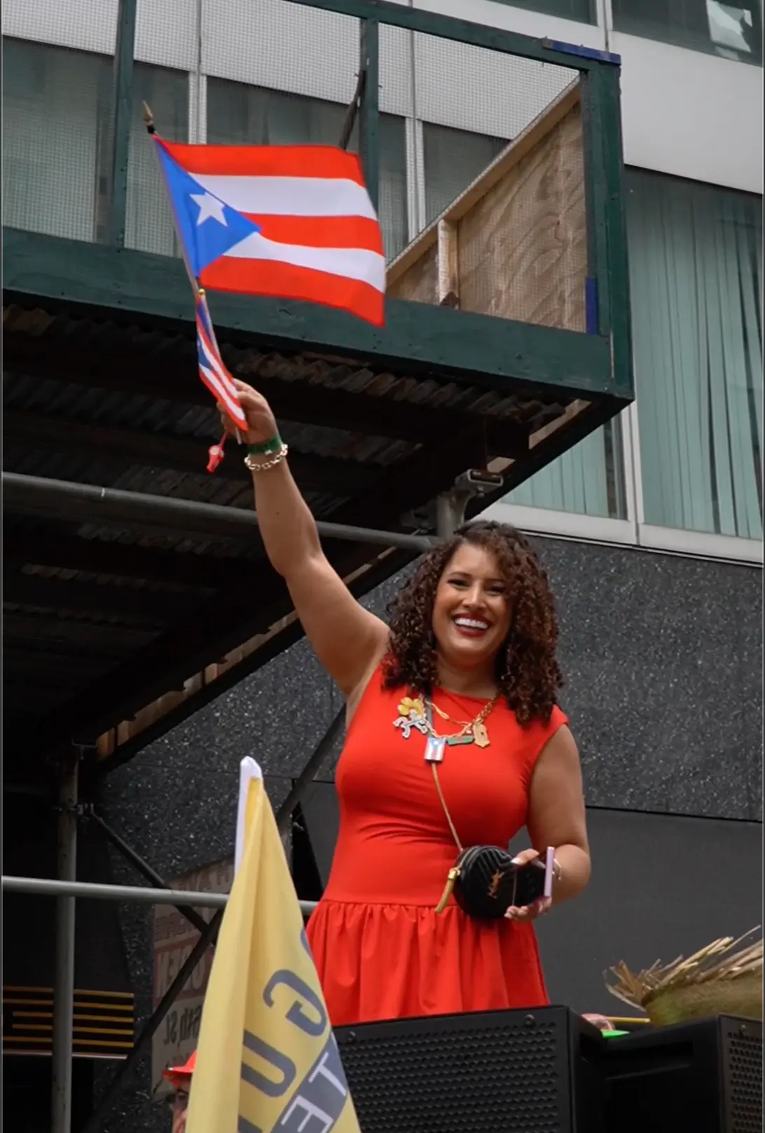 Parade guest in a red dress waving a Puerto Rican flag