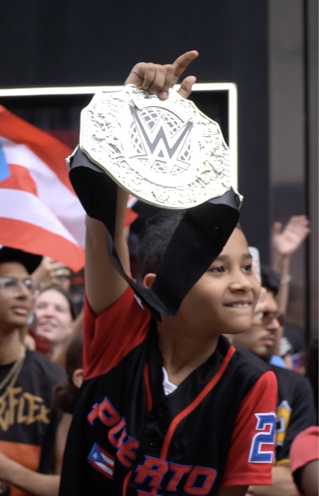 Young fan lifting a championship belt in the parade crowd